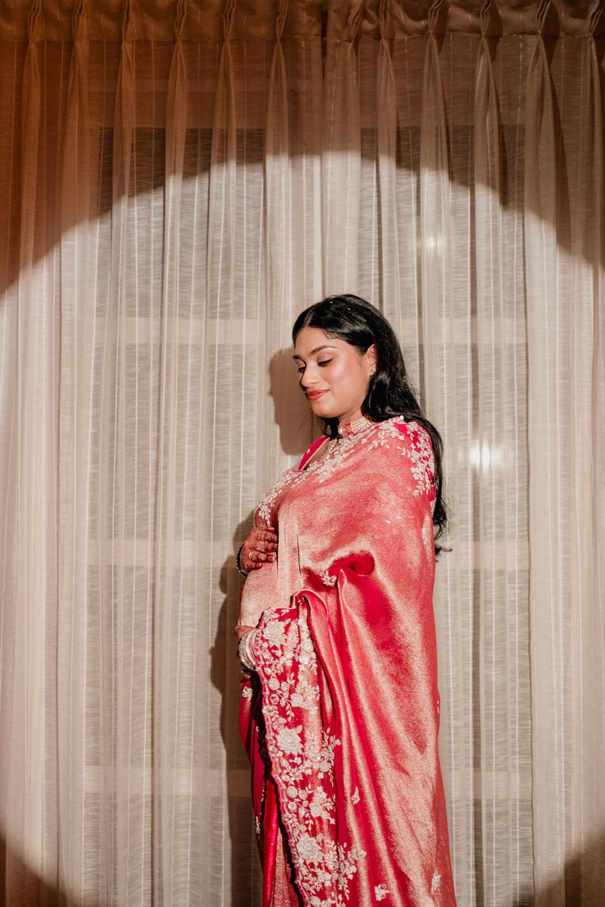 Sneha cradling her baby bump in her pink saree